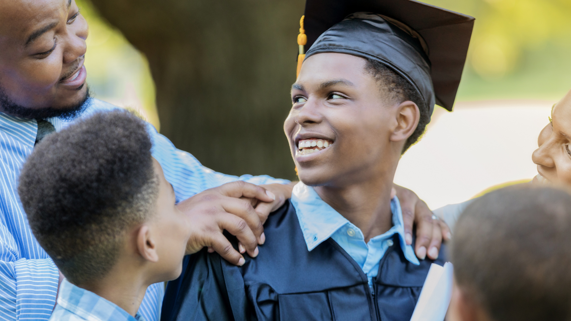 high school graduate surrounded by his family on graduation day